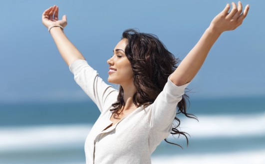 happy-woman-arms-outstretched-on-beach